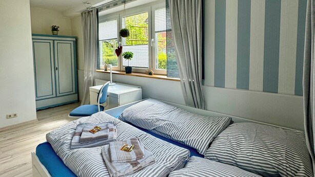 A bedroom with a bed, a desk, and a window with curtains. - Maritime vacation apartment in Wilhelmshaven on the North Sea (Wilhelmshaven)