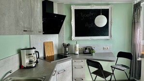 A modern kitchen with a built-in stove, a coffee maker, and a chalkboard with writing. - Maritime vacation apartment in Wilhelmshaven on the North Sea (Wilhelmshaven)