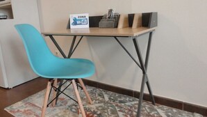 Un petit espace de travail avec une chaise bleue, une table en bois et un panneau indiquant une zone Wi-Fi.