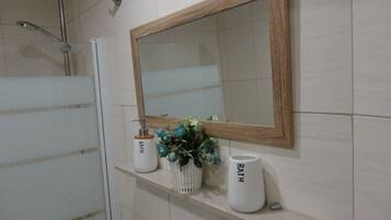 Un baño con un espejo grande, una ducha y dos jarrones blancos con la palabra "BATH" en ellos.