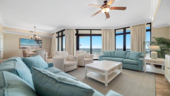 A spacious living room with a large sofa, a coffee table, and a dining area with a view of the ocean. - 3rd Floor!! New Owner, New to the Rental Market, Lazy River and Slide!! (Orange Beach)