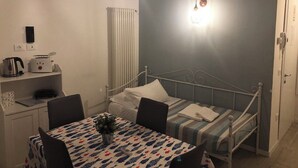 Un dormitorio pequeño con una cama individual, mesita de noche y un rincón de escritorio con hervidor y tostadora.