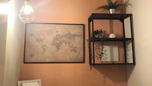 Una habitación con un mapa en la pared, una lámpara colgante, una estantería con plantas y un espejo.
