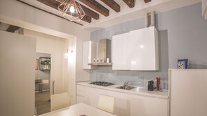 Una cocina moderna con armarios blancos, una estufa a gas y un comedor con mesa y sillas.