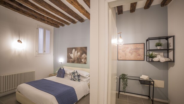 Un dormitorio con cama, mesita de noche y estante en la pared con toallas.