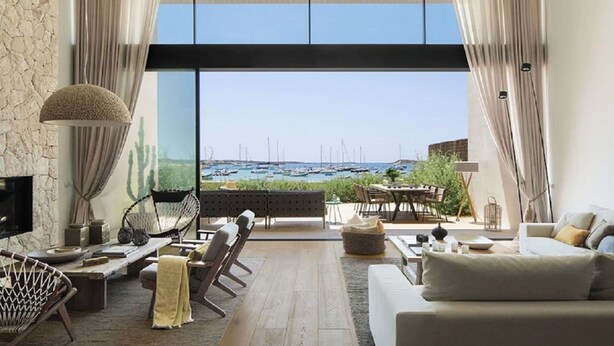 A spacious living area with a large window overlooking a marina, a stone wall, a sofa, a dining table, and a hammock.