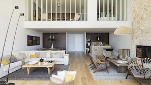 A spacious living area with a high ceiling, a dining table, a sofa set, and a kitchen in the background.