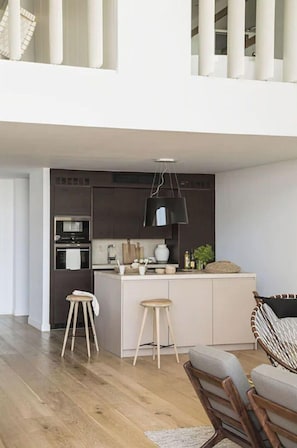 A modern kitchen with dark cabinetry, a central island, and wooden stools. - NEW STYLISH HOUSE LOCATED ON THE BEACH (Colònia de Sant Jordi)