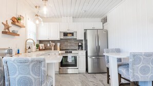 Una cocina moderna con armarios blancos, electrodomésticos de acero inoxidable y una isla central con taburetes de bar.