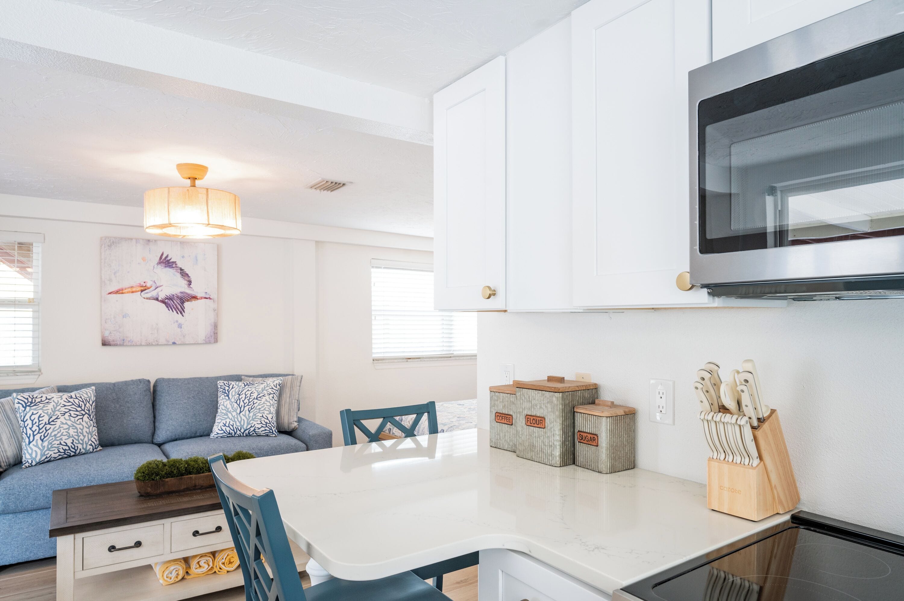 Une cuisine moderne avec des meubles blancs, une grande cuisinière et un coin repas comprenant une chaise bleue et une table blanche.