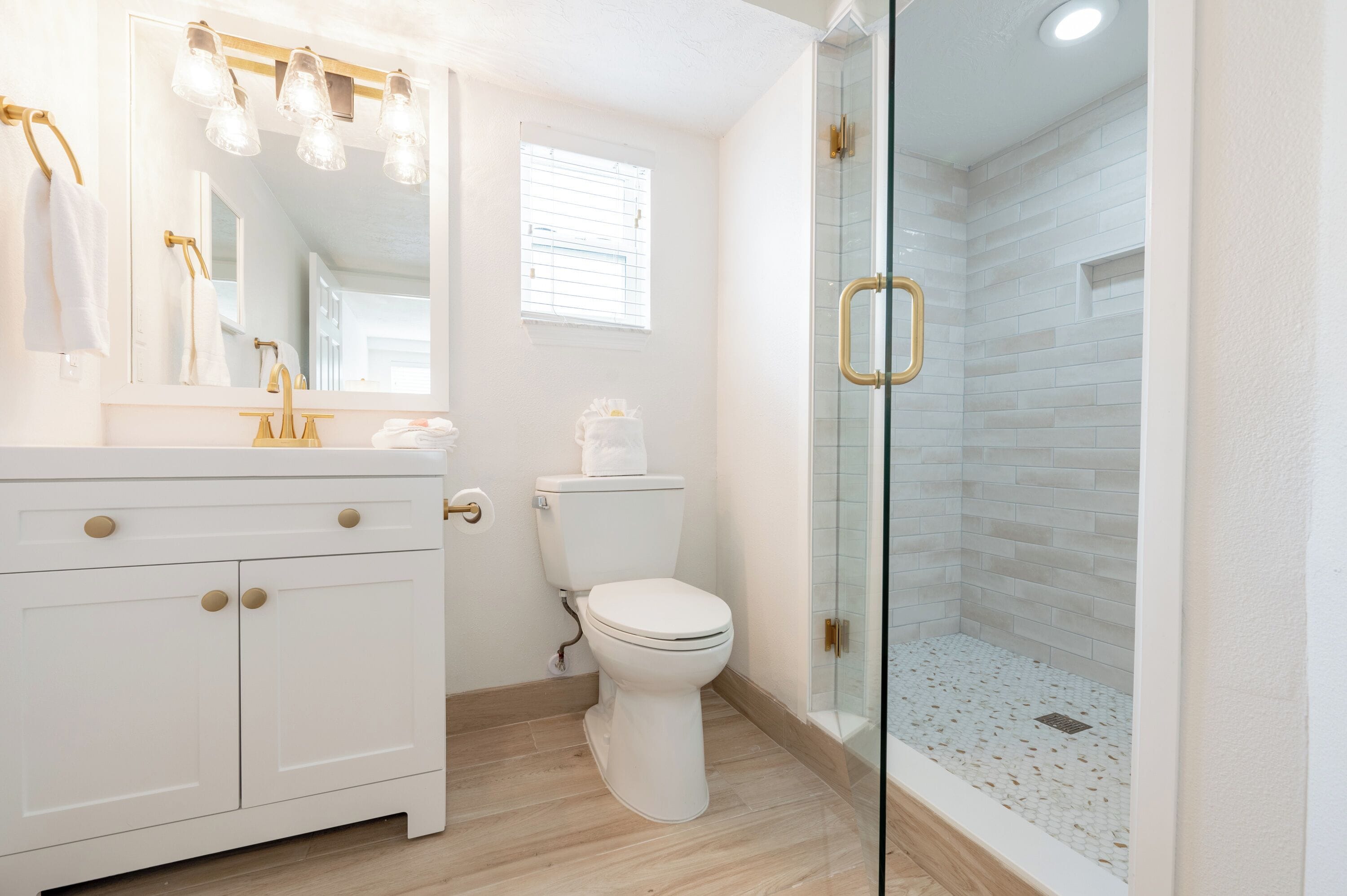 A modern bathroom with a white vanity, a toilet, and a glass-enclosed shower.