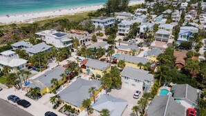 An aerial view of a coastal residential area with houses, a beach, and a clear sky. - Anna Maria Beach Cottage 110  Traditional beach cottage, moments from the sand! (Anna Maria)