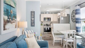 Una sala de estar moderna con un sofá azul, una mesa de comedor con sillas y una cocina al fondo.