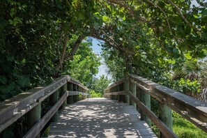 A wooden boardwalk surrounded by dense foliage. - Charming Cottage with modern amenities close to beach w/ pool, beach gear, bikes (Anna Maria)