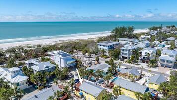 A coastal residential area with houses, a beach, and a clear blue sky.