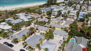 An aerial view of a coastal residential area with houses, a beach, and a clear sky. - Anna Maria Beach Cottage 110G  Updated beach cottage, with pool and beach gear! (Anna Maria)