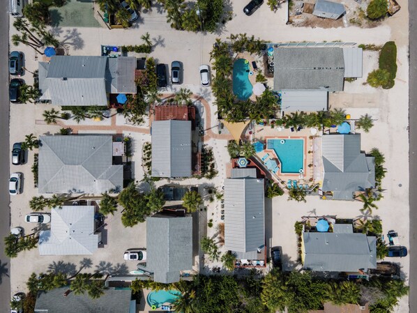 Vue aérienne d’un quartier résidentiel avec de nombreuses maisons, une piscine et des voitures garées.