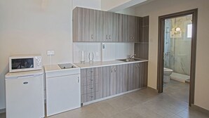 A modern kitchen with grey cabinets, a white countertop, a microwave, and a sink. - 5 Star Apartment for Rent in Cyprus, Ayia Napa Apartment 1325 (Ayia Napa)
