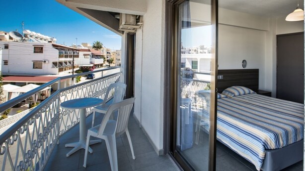 A balcony with a bed, a table, and two chairs. - 5 Star Apartment for Rent in Cyprus, Ayia Napa Apartment 1325 (Ayia Napa)