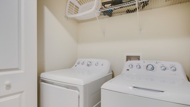Une buanderie équipée de deux machines à laver à chargement frontal blanches et d’un étendoir à linge blanc.