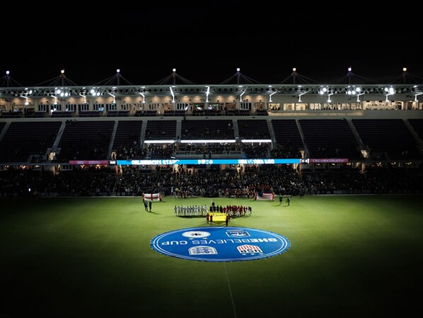 A stadium with tiered seating and a central field marked for a sports event.