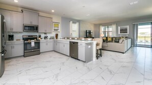 A modern kitchen with a central island, built-in appliances, and a dining area with a sofa. - Luxury Mansion on Storey Lake Resort, Minutes From Disney World, Orlando Mansion 2672 (Kissimmee)