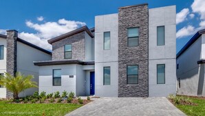 A modern multi-story residential building with a stone facade, multiple windows, and a paved entrance. - Luxury Mansion on Storey Lake Resort, Minutes From Disney World, Orlando Mansion 2672 (Kissimmee)