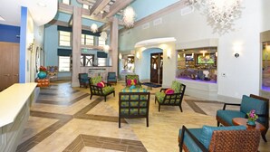 Eine geräumige Lobby mit hoher Decke, mehreren Sitzbereichen und einer Bar.
