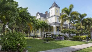 A large, yellow colonial-style building with a prominent tower, surrounded by lush greenery and a well-maintained lawn.