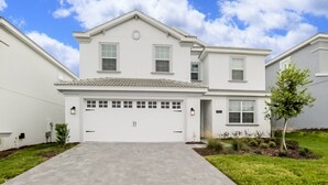 A two-story house with a garage, a small front yard, and a clear sky. - Amazing Villa on Champions Gate Resort With the Best 5 Star Amenities, Orlando Villa 2846 (Davenport)