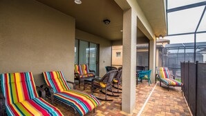 A covered patio area with striped lounge chairs and a brick floor. - The Secret to Enjoying Your Luxury Villa Holiday on Windsor at Westside Resort, Orlando Villas 2806 (Kissimmee)
