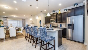 A modern kitchen with dark cabinets, stainless steel appliances, and a central island with bar stools. - The Secret to Enjoying Your Luxury Villa Holiday on Windsor at Westside Resort, Orlando Villas 2806 (Kissimmee)