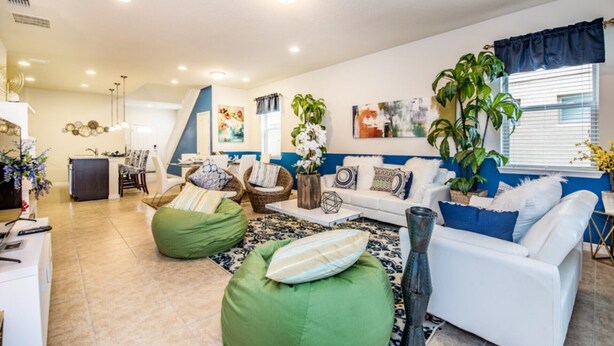 A modern living room with a white sofa, green bean bag chairs, and a dining area with a kitchen in the background. - The Secret to Enjoying Your Luxury Villa Holiday on Windsor at Westside Resort, Orlando Villas 2806 (Kissimmee)
