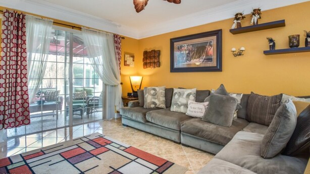 A living room with a sofa, a patterned rug, a ceiling fan, and a window with curtains. - Luxury 5 Star Villa on Highlands Reserve Resort, Orlando Villa 2748 (Davenport)
