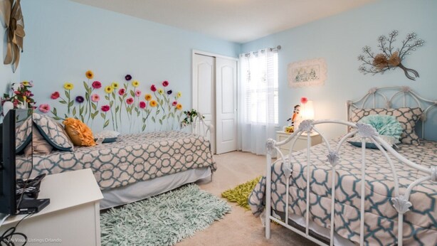 A bedroom with two beds, a desk, and a chair. There is a window with sheer curtains and a wall-mounted decoration. - Picture Renting Your Own Luxury Mansion on the Exclusive Windsor at Westside Resort, Close to Disney, Orlando Mansion 3178 (Kissimmee)