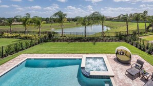 Une piscine avec un jacuzzi, entourée d’une pelouse bien entretenue et avec un terrain de golf en arrière-plan.