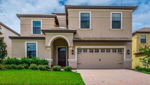 A two-story house with a beige facade, a dark brown front door, and a garage with a number "1308" on the garage door. - Your Beautiful Mansion Close to Disney on the Prestigious Champions Gate Resort, Orlando Mansion 2508 (Davenport)