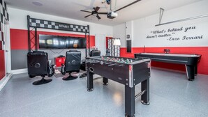 A room with a foosball table, a projector screen, and a motivational quote on the wall. - Your Beautiful Mansion Close to Disney on the Prestigious Champions Gate Resort, Orlando Mansion 2508 (Davenport)