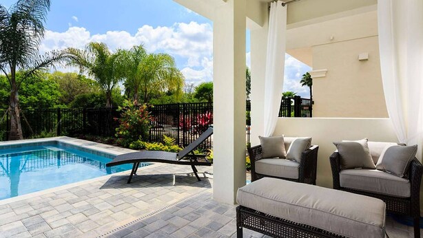 A pool area with a lounge chair and ottoman, surrounded by greenery and a fence. - 5 Star Villa With Private Pool on Reunion Resort and Spa, Orlando Villa 4591 (Kissimmee)