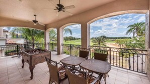 A covered outdoor area with a pool table, chairs, and a foosball table. It features a view of a golf course and palm trees. - 5 Star Villa on Orlandos Most Exclusive Reunion Resort and Spa, Orlando Villa 4599 (Kissimmee)