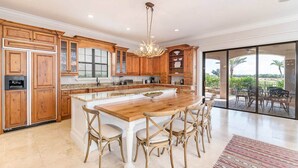 A spacious kitchen with wooden cabinets, a large island, and a view to an outdoor patio. - 5 Star Villa on Orlandos Most Exclusive Reunion Resort and Spa, Orlando Villa 4599 (Kissimmee)
