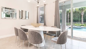 Un comedor moderno con una mesa redonda, seis sillas grises tapizadas y un cuenco decorativo como centro de mesa.