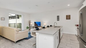 Een moderne keuken met een centraal eiland, een zithoek met een bank en een groot raam.
