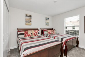 A bedroom with two beds, each with striped bedding and floral pillows. There are two wall-mounted paintings above the beds. - Imagine You and Your Family Renting This 5 Star Villa on Storey Lake Resort, Orlando Townhome 5054 (Kissimmee)