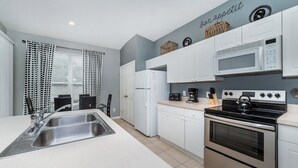 Una cocina moderna con un fregadero, estufa, microondas y armarios blancos.