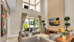A spacious living room with a large window, a flat-screen TV, and a dining area. - 5star Villa Close to Disney, Orlando Townhome 3701 (Kissimmee)