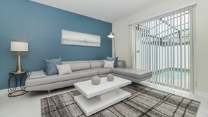 Ein modernes Wohnzimmer mit einem grauen Ecksofa, einem weißen Couchtisch und einem gemusterten Teppich.