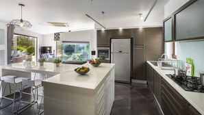 A modern kitchen with a central island, stainless steel appliances, and a large window overlooking a garden. - At Last You can Rent the Perfect Luxury Villa in Protaras Close to all the Action, Protaras Villa 1569 (Paralimni)
