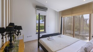 A bedroom with a bed, bedside lamps, a window, and an air conditioning unit. - At Last You can Rent the Perfect Luxury Villa in Protaras Close to all the Action, Protaras Villa 1569 (Paralimni)