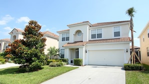 A two-story house with a white garage door, a front entrance, and a small porch. - Beautiful 5 Star Villa With Private Pool on the Prestigious Windsor Hills Resort, Orlando Villa 4766 (Kissimmee)